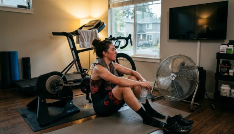 Cyclist sitting in front of a running floor fan during a post workout cooling routine after an intense indoor cycling session